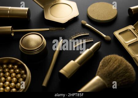 golden decorative makeup cosmetics on black table. luxury beauty products concept Stock Photo