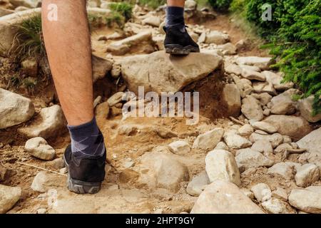 Hiking in Carpathian mountains. Close up of hiker's shoes. Man walking on rocks stepping on stone. Active lifestyle Stock Photo