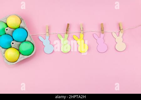 Easter. Box of colorful eggsand easter decoration of the room on a pink background. Easter composition for design. Place for text Stock Photo