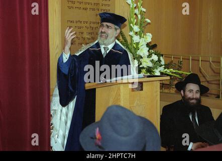 The Chief Rabbi Jonathan Sacks was the guest of honour for the celebration of the Solihull Hebrew Congregation's 25th Anniversary. During his visit he met children in the lounge of a family from the congregation. He talks informally to young Jewish children about their work achieved at the synagogue's Cheder (classroom), minister of the congregation Rabbi Yehuda Pink looks on. He spoke during a the commemoration service on 27th October 2002.The Mayor of Solihull Cllr. Kate Wild attended and was presented with a bouquet from Cheder pupil 13 year old Zipporah Gershon Stock Photo