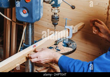 Drilling holes in wooden board. Making wooden legs for easels. Joinery work. Stock Photo