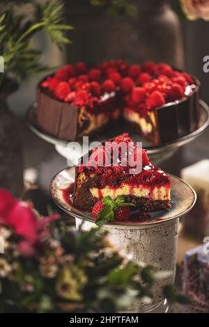 Slice of chocolate vanilla cake with raspberry jelly topping and decorated with fresh raspberries Stock Photo