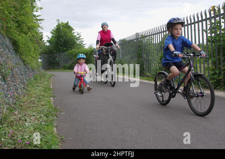 Mother cycling and guiding young children on cycle path Stock Photo