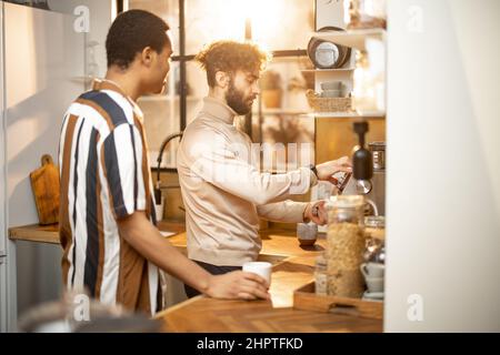 Two men talking and drinking coffee on kitchen at home Stock Photo