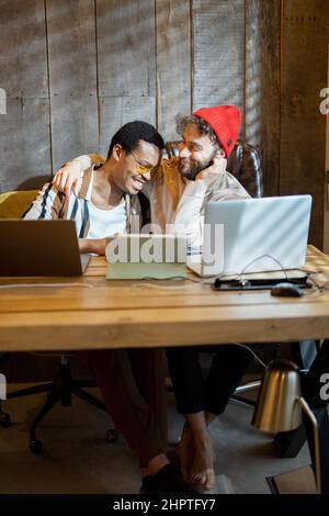 Gay couple working on computers at home office Stock Photo