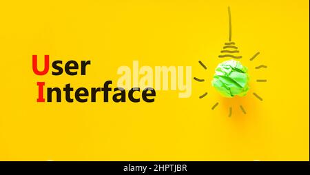 UI user interface symbol. Concept words UI user interface. Green light bulb icon. Beautiful yellow background. Copy space. Business and UI user interf Stock Photo