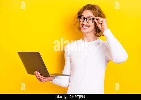 Photo of dreamy cheerful guy wear white shirt arm spectacles working modern gadget isolated yellow color background Stock Photo