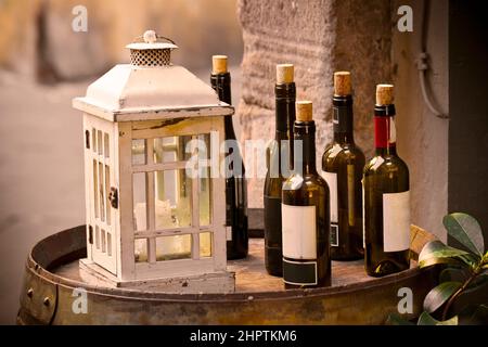 Red wine bottles uncorked over a wooden barrel with lantern. Stock Photo