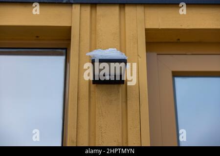 Close up view of outdoor led waterproof solar lamp with motion sensor covered with snow. Sweden. Stock Photo