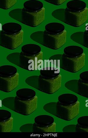 Pattern of glass jars of eatable adjika green sauce.Pop-art style. Good for web-banners, stories, background. Stock Photo