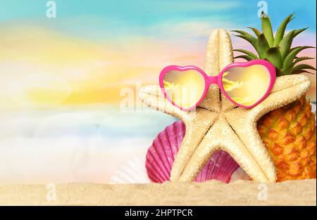 Summer tropical sea with pineapple, starfish and sunglasses on hot sand beach. Travel and vacation concept with copy space. Stock Photo