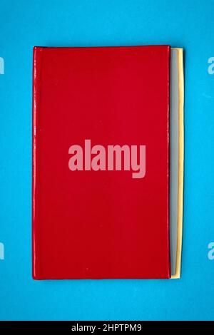 Closed book with blank red hardcover on blue background Stock Photo