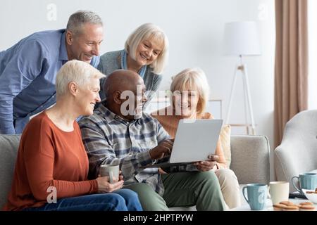Positive elderly people spending time together at home, using gadgets Stock Photo