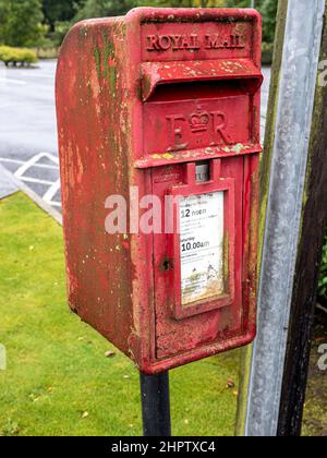 Small Damp  Royal Mail box: A small roadside royal mail post box in the village of Raffry in Norther Ireland. The damp climate has decorated the box with lichen, algea and rust. Stock Photo