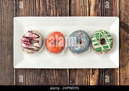 Delicious colorful mini donuts with coffee on wooden table Stock Photo