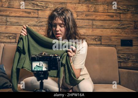 Female video blogger records content or online streaming at home. Cute young woman vlogger in front of camera talking about fashion clothes. Stock Photo