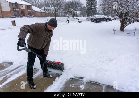 Old retired man clears snow off of driveway Stock Photo