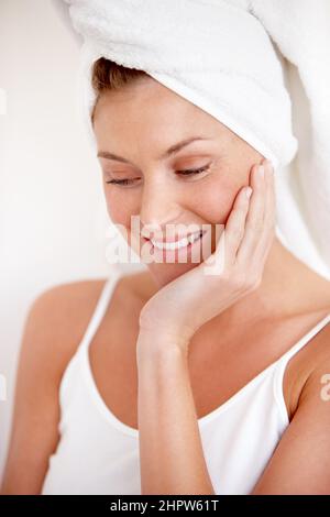 Amazed at how smooth her skin is. A lovely young woman feeling her smooth skin after a refreshing shower. Stock Photo