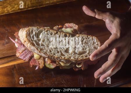 Pastrami sandwich on a wooden tablet with delicious meet on baguette bread with cheese,copy space in parts of the image. Stock Photo