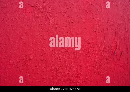 Texture of rough concrete wall covered and painted red decorative stucco. Background of blood-red colored plaster with cracks on concrete wall.  Stock Photo