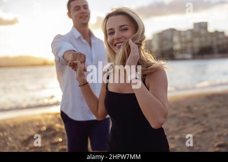 Portrait of beautiful woman holding hand of man standing behind Stock Photo