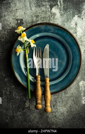 Minimalistic spring table setting decorated with fresh daffodil flowers on concrete background Stock Photo