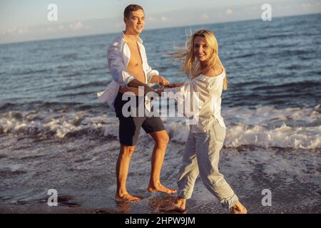 Smiling man and woman standing on seashore against the background of sea Stock Photo