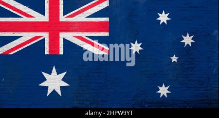 Full frame photo of a weathered flag of Australia painted on a plastered brick wall. Stock Photo