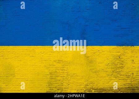 Full frame photo of a weathered flag of Ukraine, painted on a plastered brick wall. Stock Photo