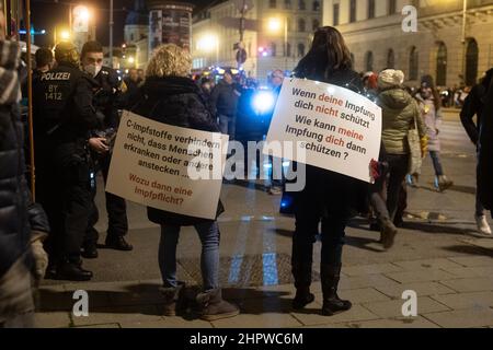 Munich, Germany. 23rd Feb, 2022. Participants with signs „Covid-19 vaccines don't prevent people from getting sick or infecting others“ and „If your vaccination doesn't protect you. How can my vaccination protect you then“. On February 23, 2022, hundreds of anti-vaxxers gathered to demonstrate against mandatory vaccination and covid protection measures. They lined up between the Geschwister-Scholl-Platz and Odeonsplatz to form a chain of lights. The mask obligation and distance rules were hardly kept. (Photo by Alexander Pohl/Sipa USA) Credit: Sipa USA/Alamy Live News Stock Photo