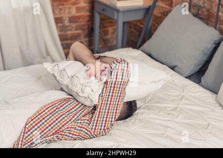 frustrated upset middle-aged jobless man crying and covering his face with white pillow. High quality photo Stock Photo