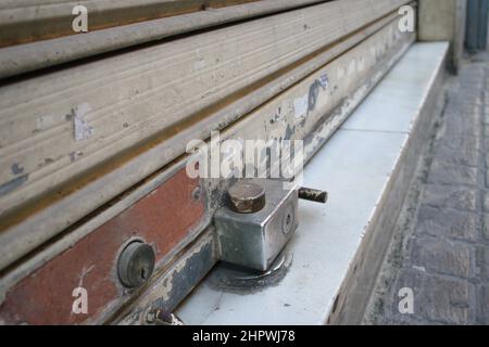 Image of a metal shutter of a commercial premises that is closed with a padlock Stock Photo
