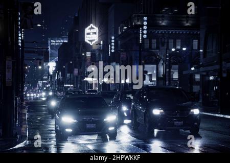 Toronto, Canada - 10 30 2021: Night rain pouring down on cars standing on traffic lights in Yonge street in downtown Toronto with bright colorful Stock Photo