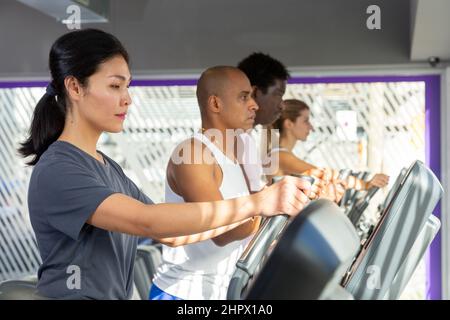 People having running elliptical trainer class in club Stock Photo