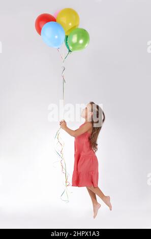 Floating away. A young girl being lifted in the air by a bunch of colourful balloons.