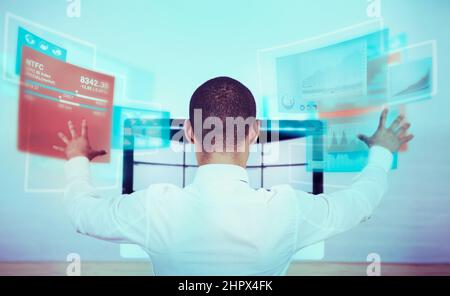 A rear view shot of a man using a futuristic computer. All screen content is designed by us and not copyrighted by others, and upon purchase a user Stock Photo