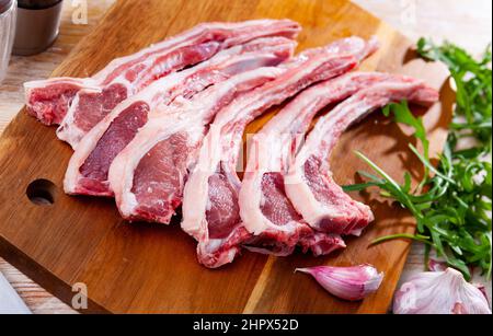 Raw mutton chops on wooden cutting board with herbs and spices Stock Photo