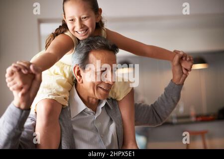 Grandpa is so fun. Shot of a grandfather giving his little granddaughter a piggy back. Stock Photo