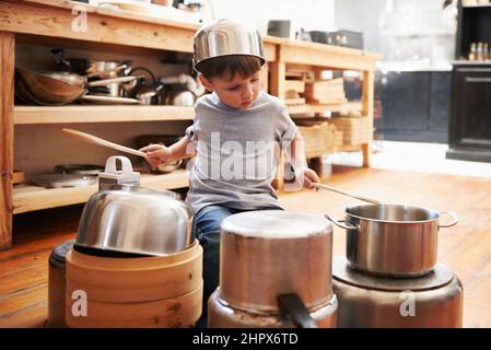 Rock star in the making. A young boy playing drums on pots and pans. Stock Photo