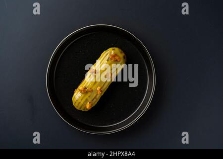 dessert is a small puff pastry pie with stuffing inside on a black serving plate on a black background . A piece of cake with a cut Stock Photo
