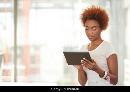 Exploring the internet. Shot of a young businesswoman using a digital tablet in the office. Stock Photo