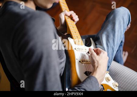 A man playing electric guitar on a bed Stock Photo