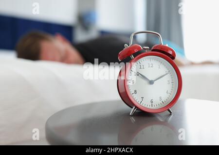 A red alarm clock stands on table in the bedroom Stock Photo