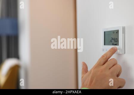 Hand sets a programmable thermostat for heating and cooling Stock Photo