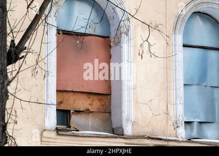 old house windows boarded up with plywood, outdoor cropped shot Stock Photo
