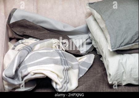 pile of crumpled blankets and pillows on a sofa, indoor closeup Stock Photo