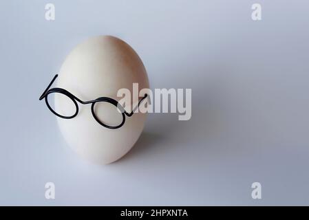 White shell egg wear glasses on white background with copy space for text Stock Photo