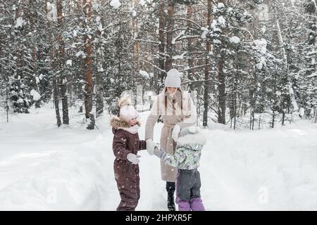 mother with two daughters walks in a snowy forest on her day off Stock Photo