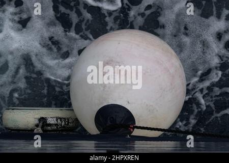 Buoy hangs on ship and foam on sea surface Stock Photo