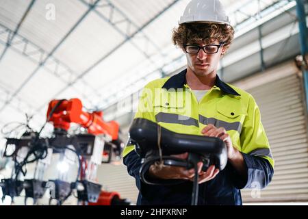 engineer checking control panel and teaching new Automatics robot arm and operating control machine in factory. Stock Photo